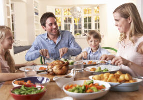 Happy family having roast chicken dinner at table