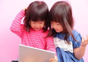 two little girls watching tablet together,Asian
